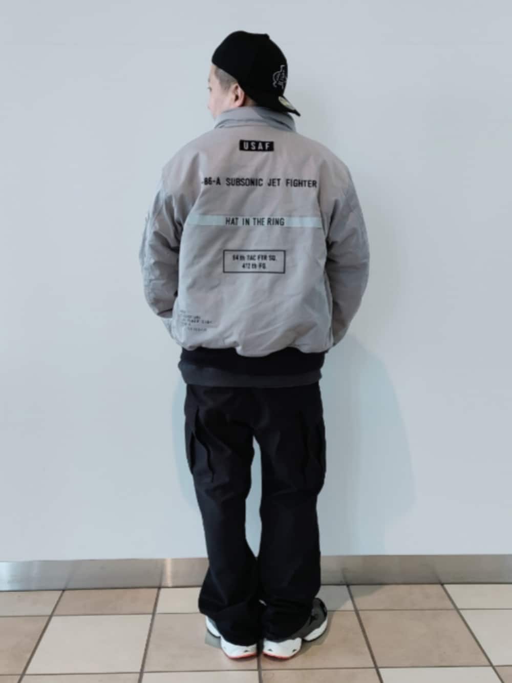 グレー系のMA-1、グレー系のTシャツ/カットソー、ブラック系のカーゴパンツを着用したメンズの冬コーディネートの2枚目の写真