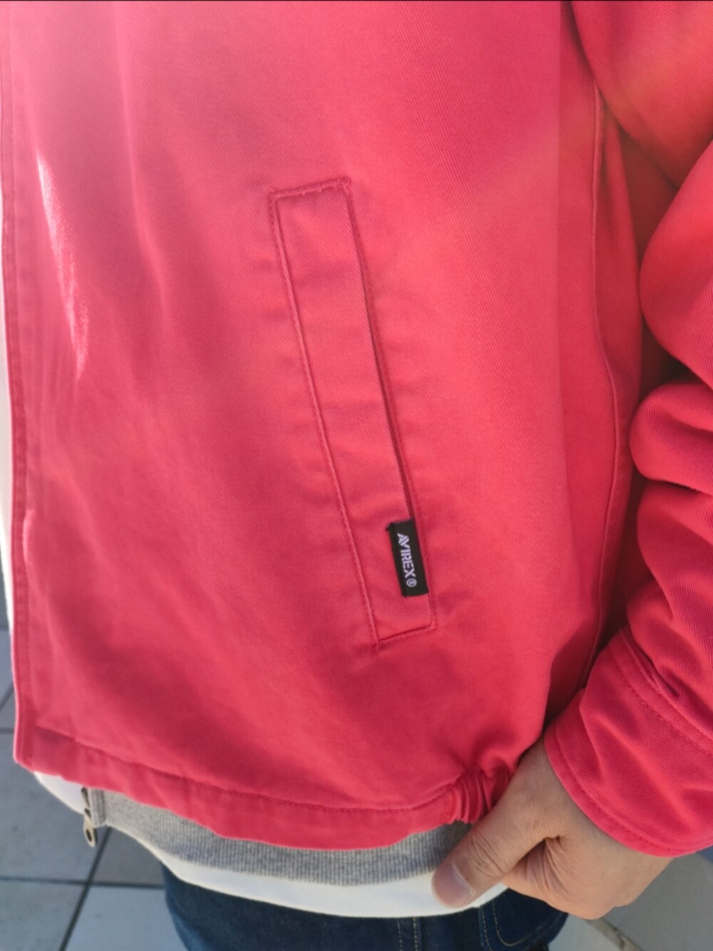 ピンク系のブルゾン、グレー系のパーカー、ブルー系のデニムパンツを着用したメンズの冬コーディネートの4枚目の写真