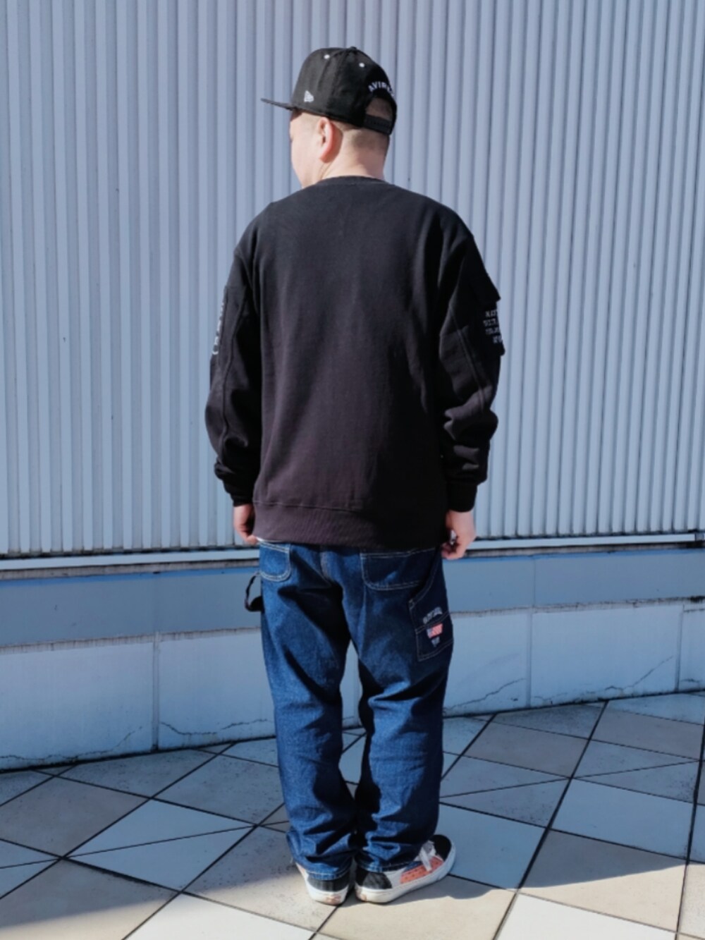 ブラック系のスウェット、ブルー系のデニムパンツ、ブラック系のキャップを着用したメンズの冬コーディネートの2枚目の写真