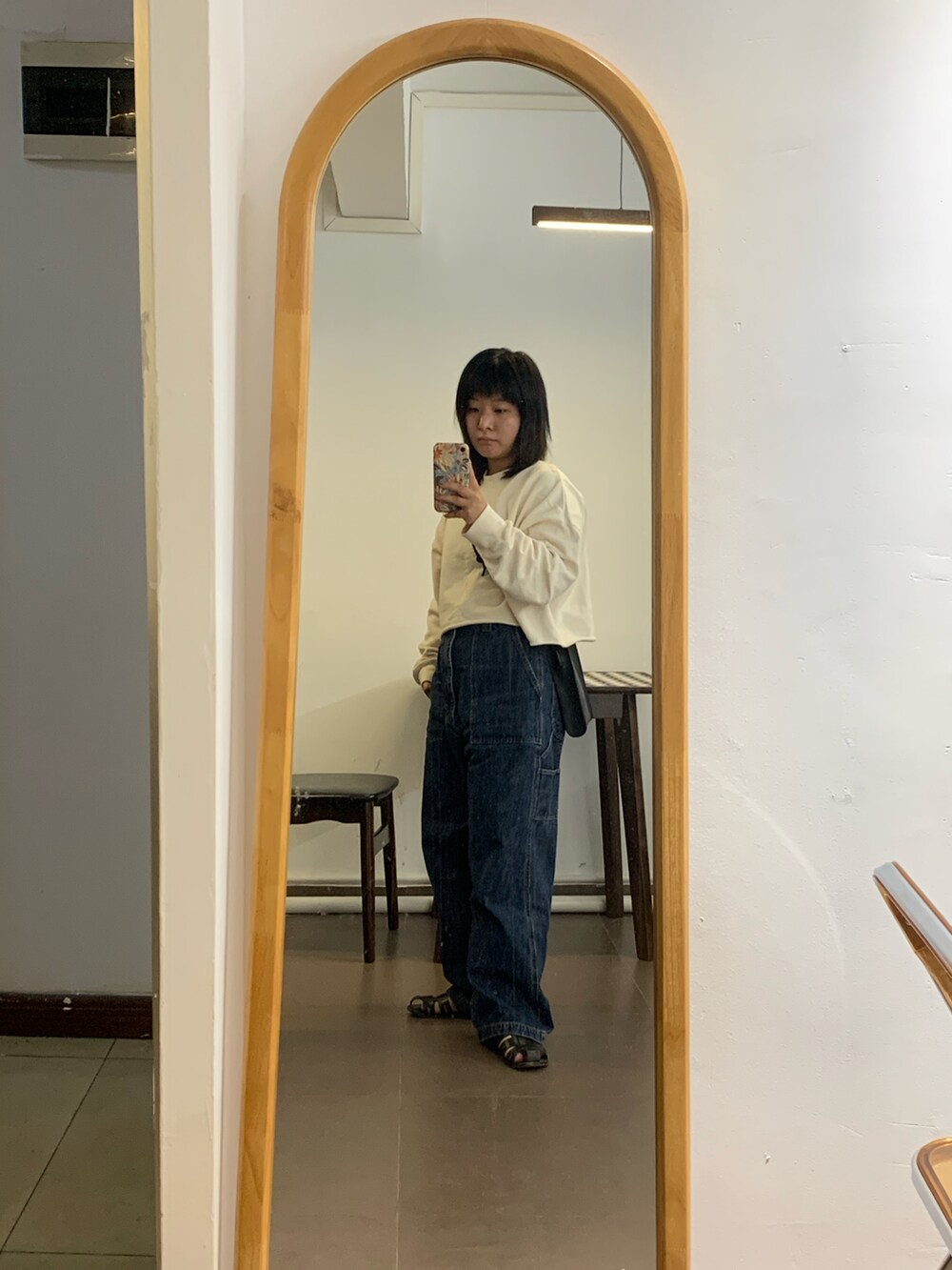 ブルー系のデニムパンツ、ブラック系のサンダル、ブラック系のハンドバッグを着用したレディースの秋コーディネートの2枚目の写真