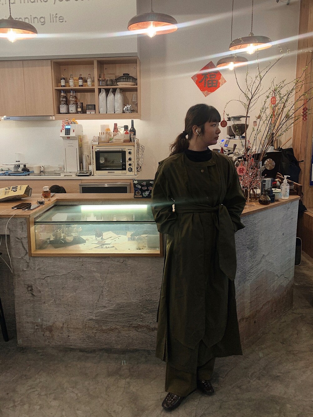 グリーン系のトレンチコート、ブラック系のその他シューズ、その他のチノパンツを着用したレディースの冬コーディネートの2枚目の写真