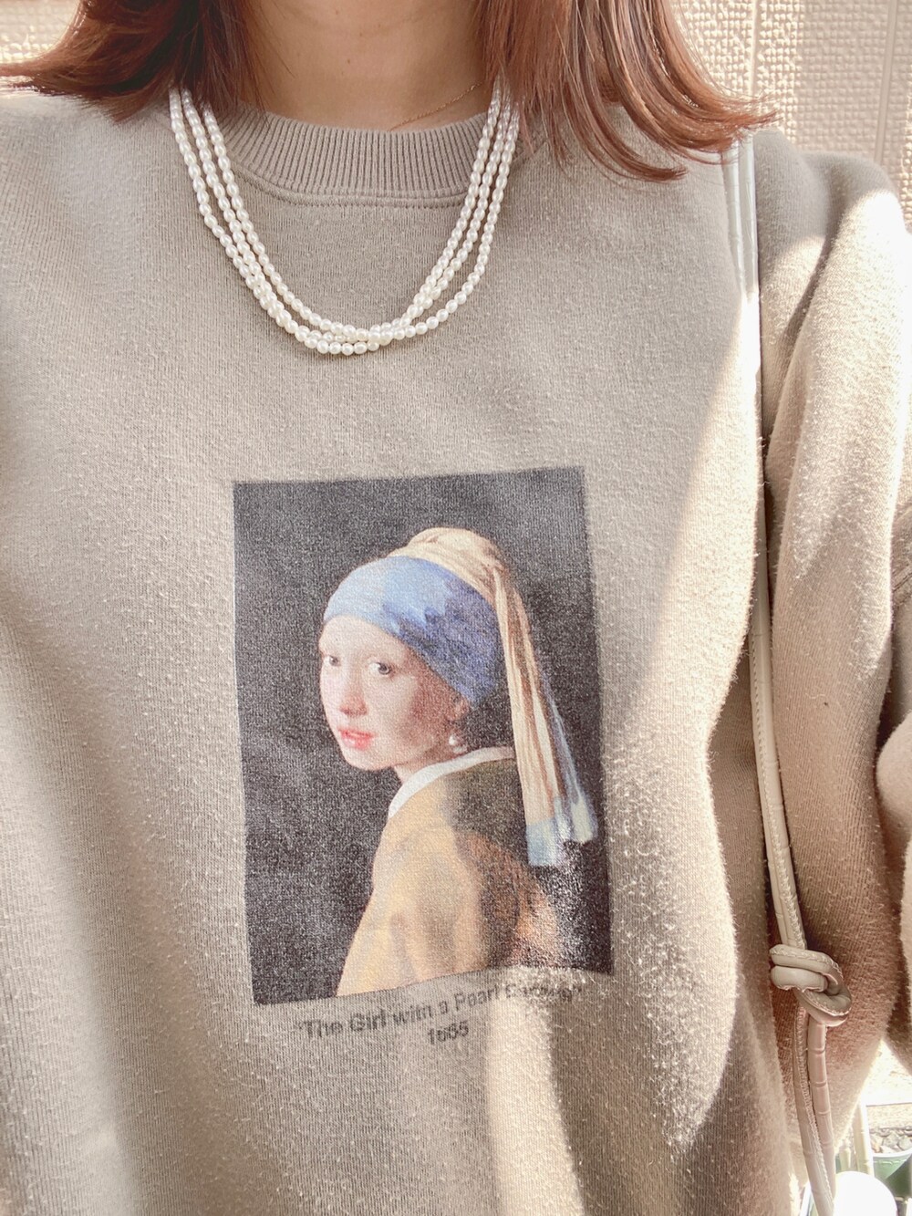 ベージュ系のスウェット、ホワイト系のスカート、ホワイト系のショルダーバッグを着用したレディースの春コーディネートの2枚目の写真