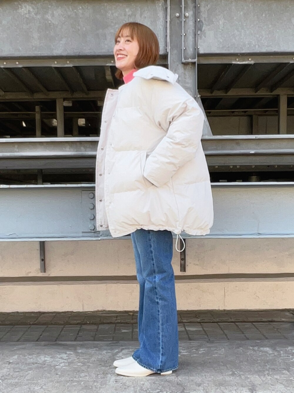 ベージュ系のダウンジャケット/コート、ピンク系のニット/セーター、ブルー系のデニムパンツを着用したレディースの冬コーディネートの2枚目の写真