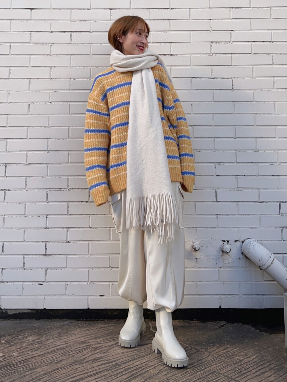 イエロー系のトップス、ホワイト系のその他パンツ、ホワイト系のブーツを着用したレディースの冬コーディネートの2枚目の写真