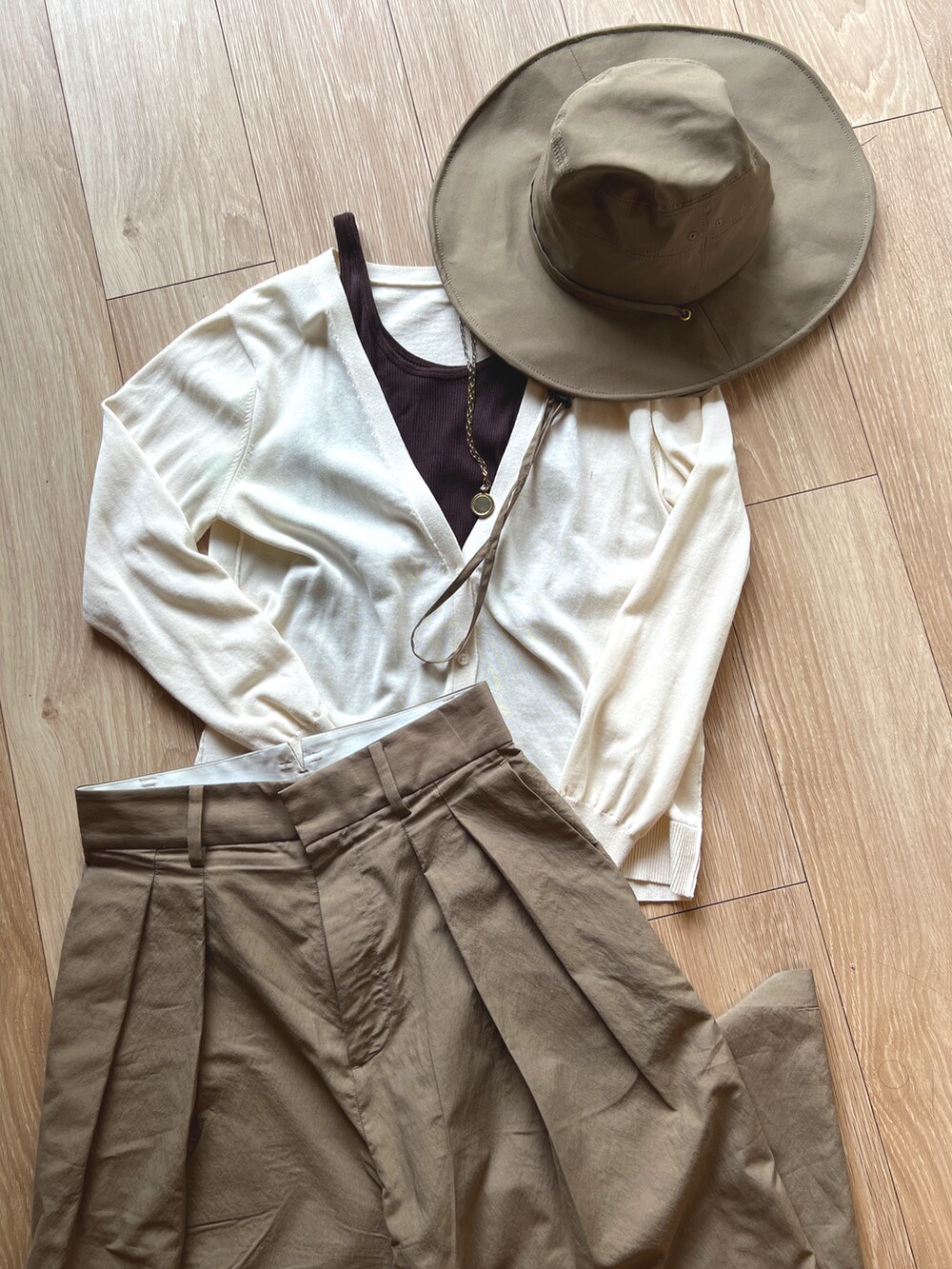 ブラウン系のTシャツ/カットソー、ホワイト系のニット/セーター、ベージュ系のチノパンツを着用したレディースの春コーディネートの2枚目の写真