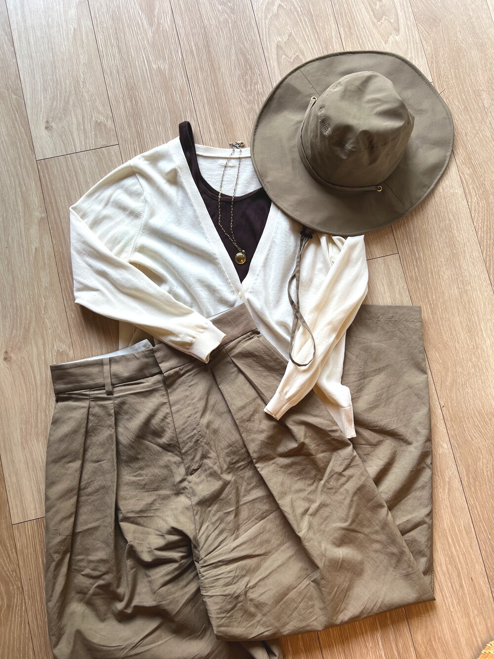 ブラウン系のTシャツ/カットソー、ホワイト系のニット/セーター、ベージュ系のチノパンツを着用したレディースの春コーディネートの3枚目の写真