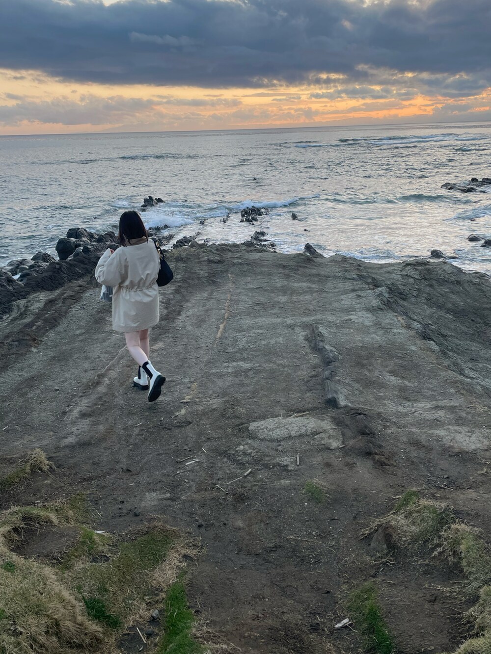 ベージュ系のミリタリージャケット、ホワイト系のブーツ、ブラック系のショルダーバッグを着用したレディースの春コーディネートの3枚目の写真