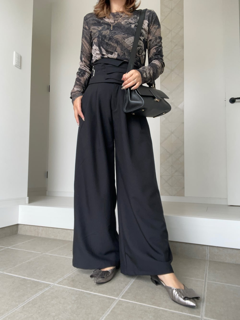 ブラック系のショルダーバッグ、ブラック系のスラックス、ブラウン系のTシャツ/カットソーを着用したレディースの春コーディネートの2枚目の写真