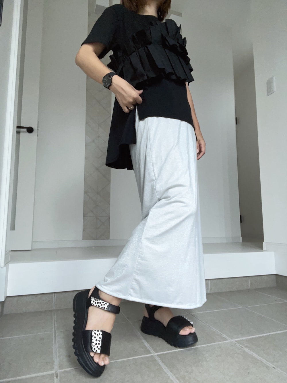 ブラック系のサンダル、ホワイト系のスカート、ブラック系のTシャツ/カットソーを着用したレディースの夏コーディネートの2枚目の写真