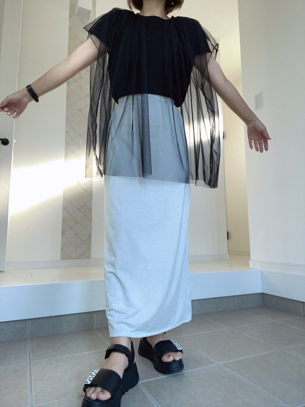 ブラック系のサンダル、ホワイト系のスカート、ブラック系のTシャツ/カットソーを着用したレディースの夏コーディネートの2枚目の写真