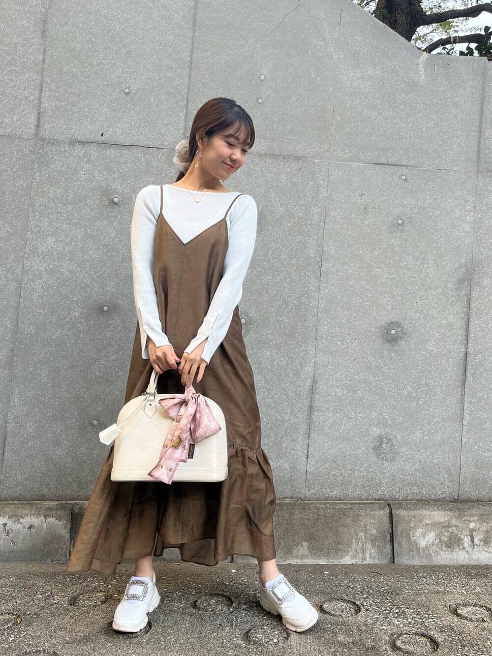 グリーン系のワンピース/ドレス、ホワイト系のニット/セーター、ホワイト系のスニーカーを着用したレディースの春コーディネートの2枚目の写真