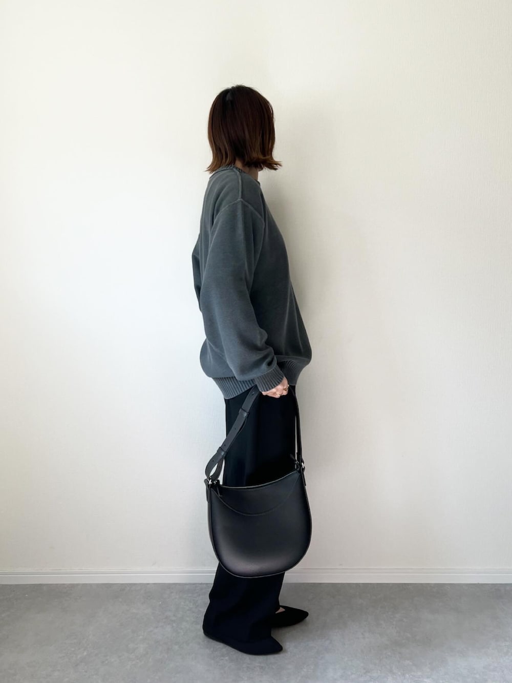 グレー系のニット/セーター、ブラック系のパンツ、ブラック系のバッグを着用したレディースの春コーディネートの2枚目の写真