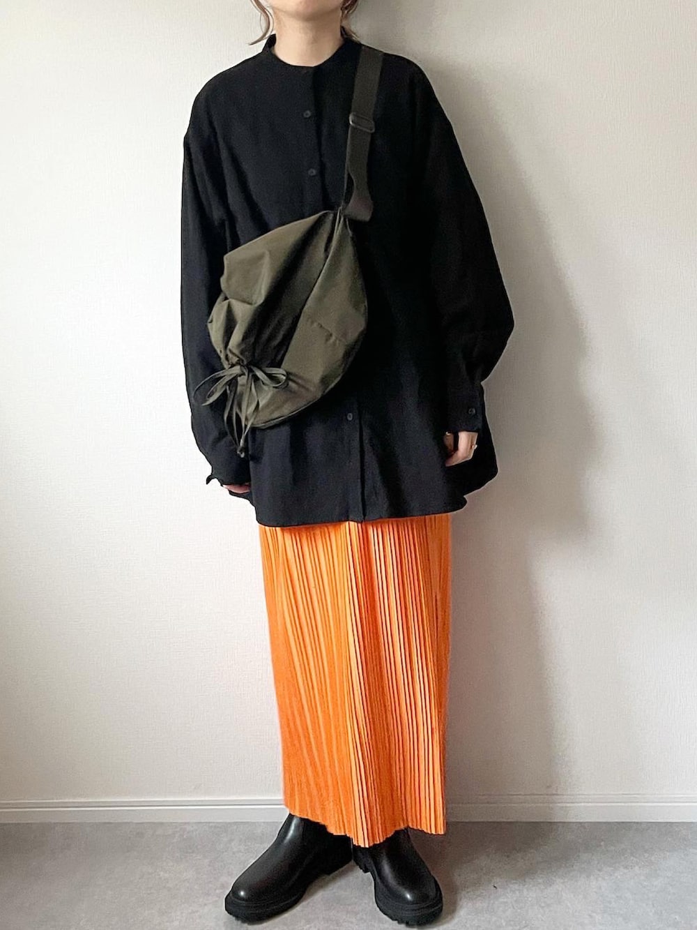 ブラック系のシャツ/ブラウス、グリーン系のショルダーバッグ、オレンジ系のスカートを着用したレディースの冬コーディネートの2枚目の写真