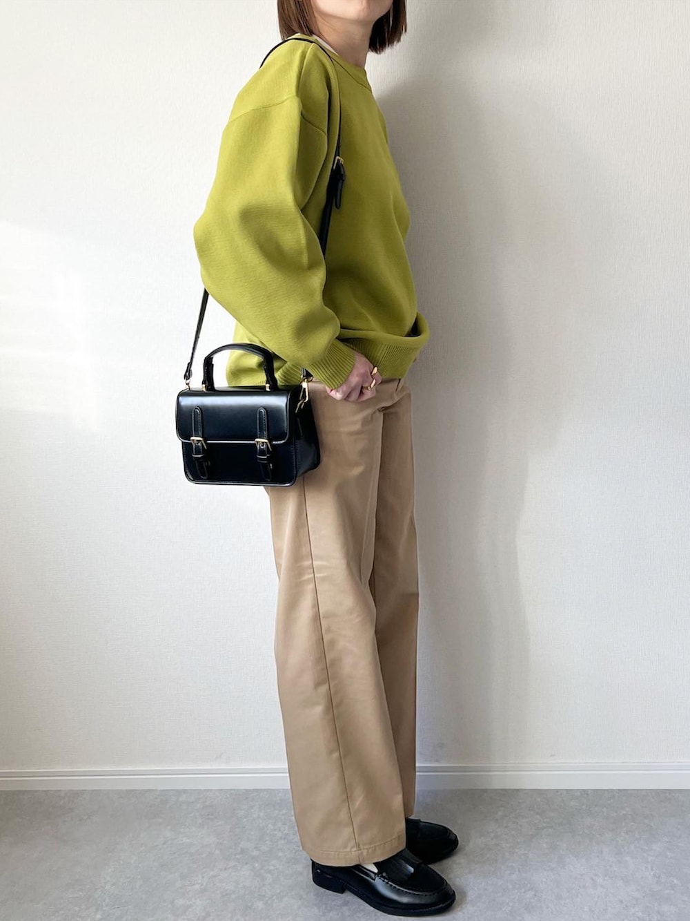 グリーン系のカーディガン/ボレロ、ホワイト系のTシャツ/カットソー、ベージュ系のチノパンツを着用したレディースの冬コーディネートの3枚目の写真