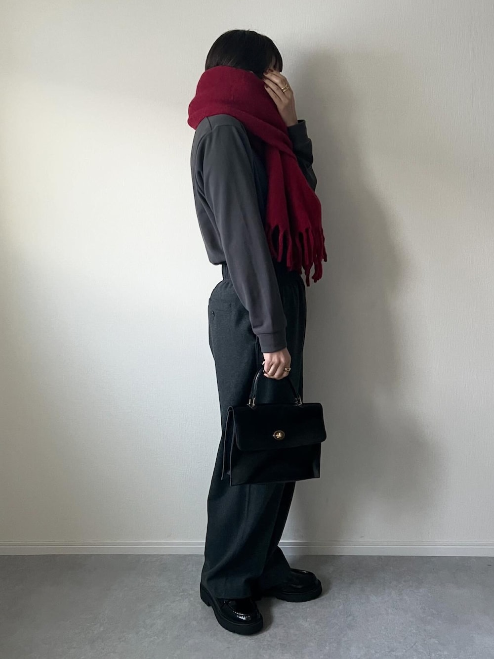 グレー系のトップス、グレー系のパンツ、ブラック系のショルダーバッグを着用したレディースの冬コーディネートの2枚目の写真