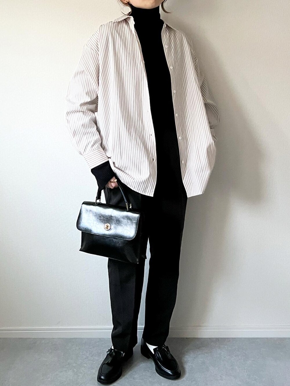 ブラック系のニット/セーター、ベージュ系のシャツ/ブラウス、ブラック系のショルダーバッグを着用したレディースの冬コーディネートの2枚目の写真