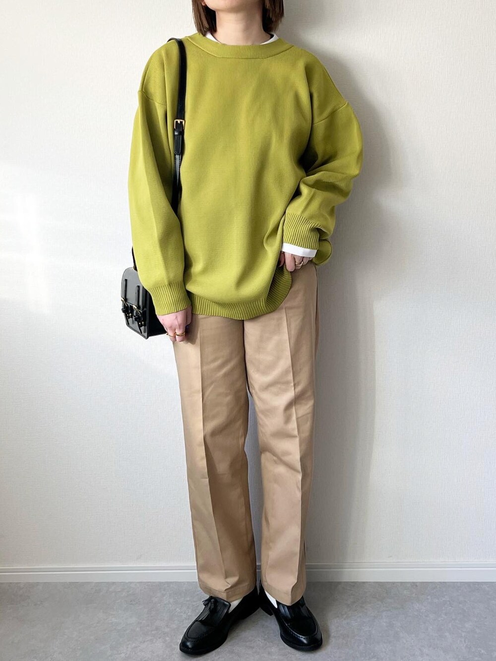 グリーン系のカーディガン/ボレロ、ホワイト系のTシャツ/カットソー、ベージュ系のチノパンツを着用したレディースの冬コーディネートの2枚目の写真