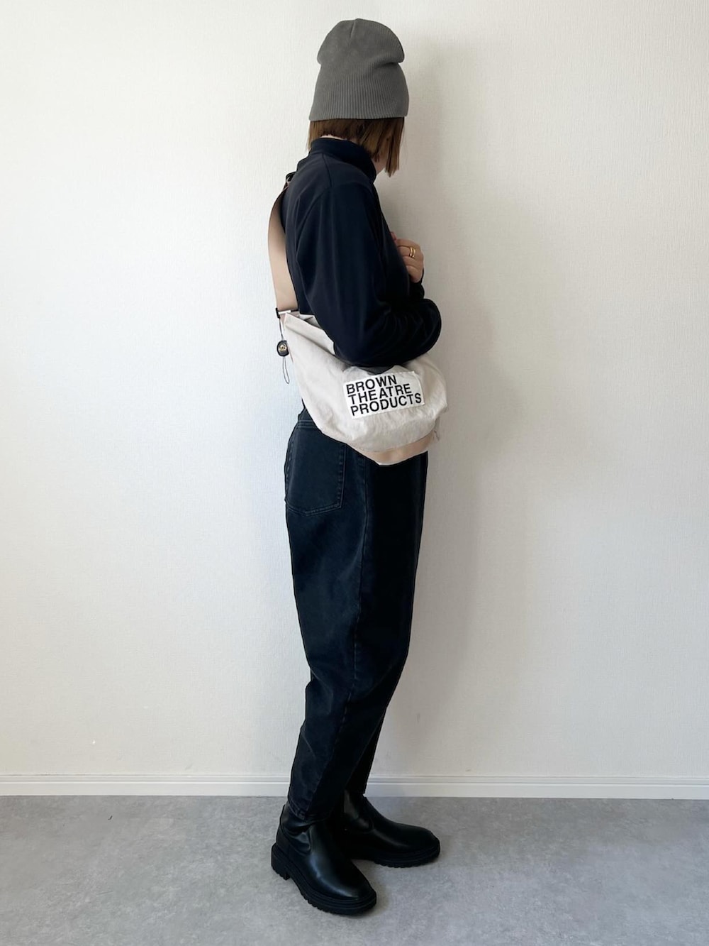 ブラック系のショルダーバッグ、ブラック系のトップス、ブルー系のデニムパンツを着用したレディースの冬コーディネートの2枚目の写真