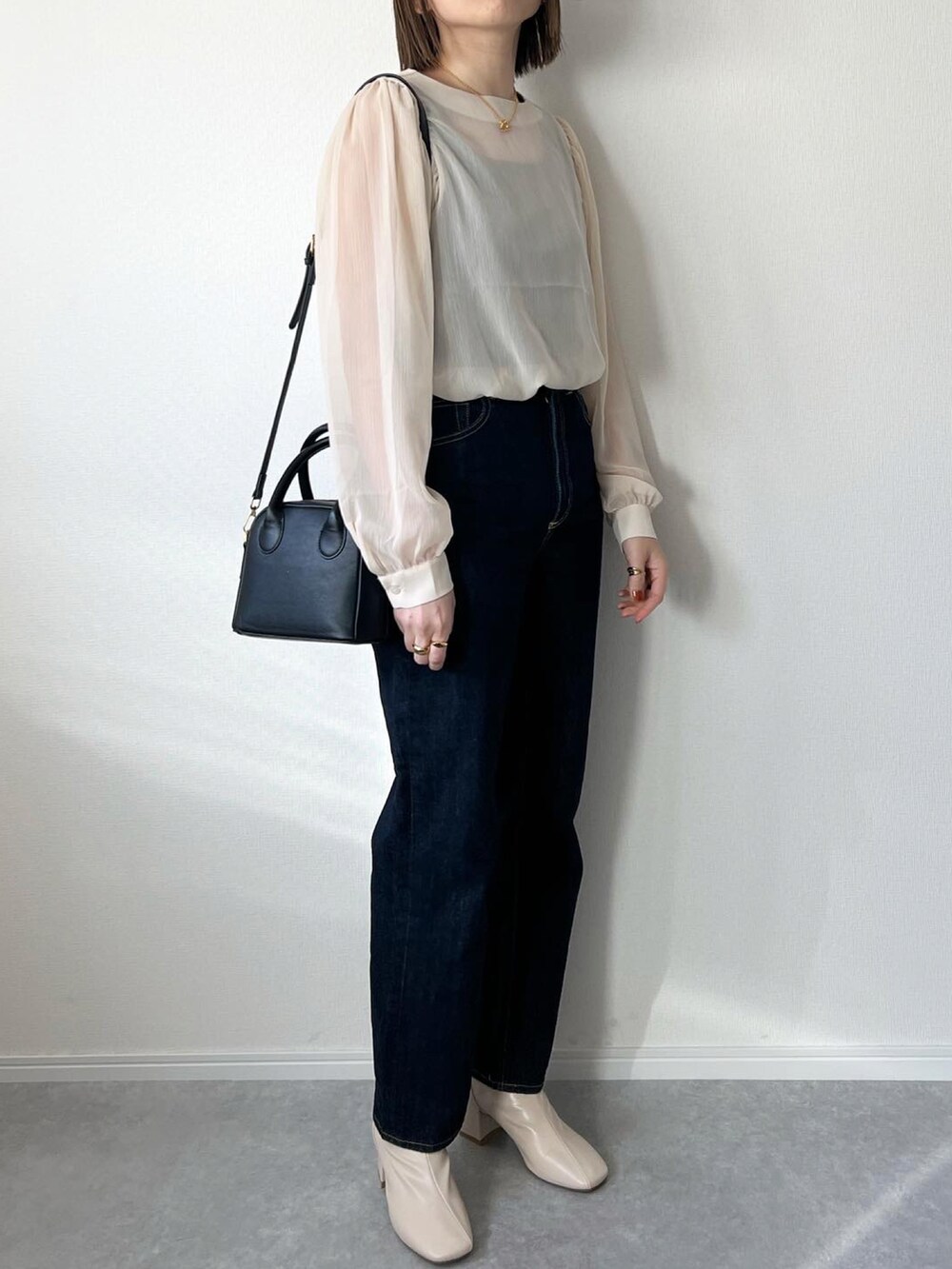 ベージュ系のシャツ/ブラウス、ブルー系のデニムパンツ、ブラック系のバッグを着用したレディースの冬コーディネートの2枚目の写真