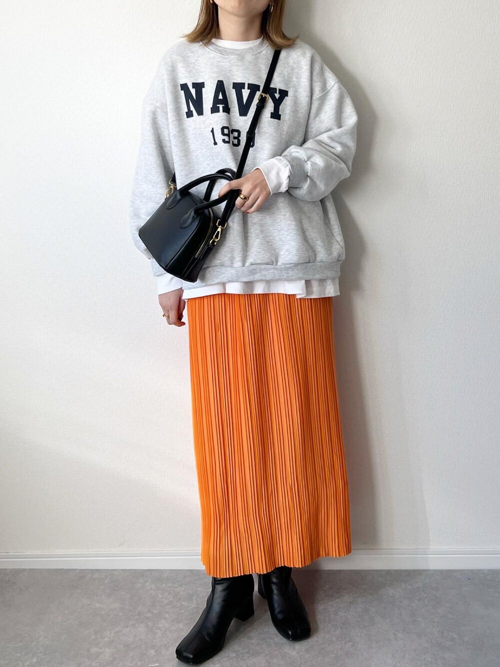 グレー系のスウェット、ブラック系のバッグ、オレンジ系のスカートを着用したレディースの秋コーディネートの2枚目の写真