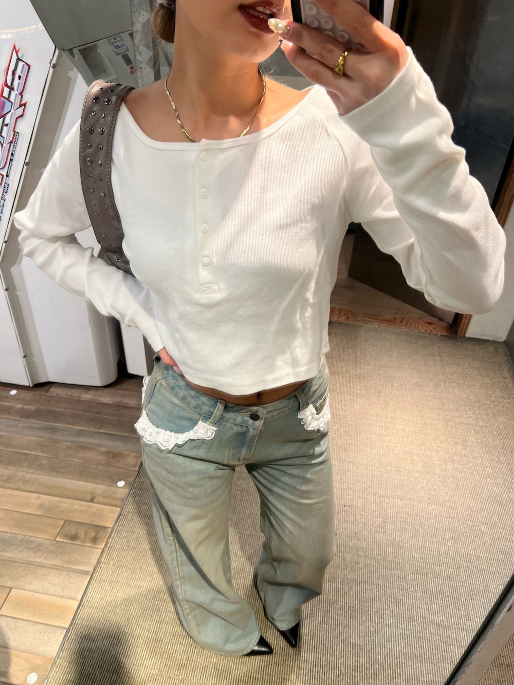 ブルー系のデニムパンツ、ホワイト系のTシャツ/カットソー、ブラック系のショルダーバッグを着用したレディースの春コーディネートの3枚目の写真