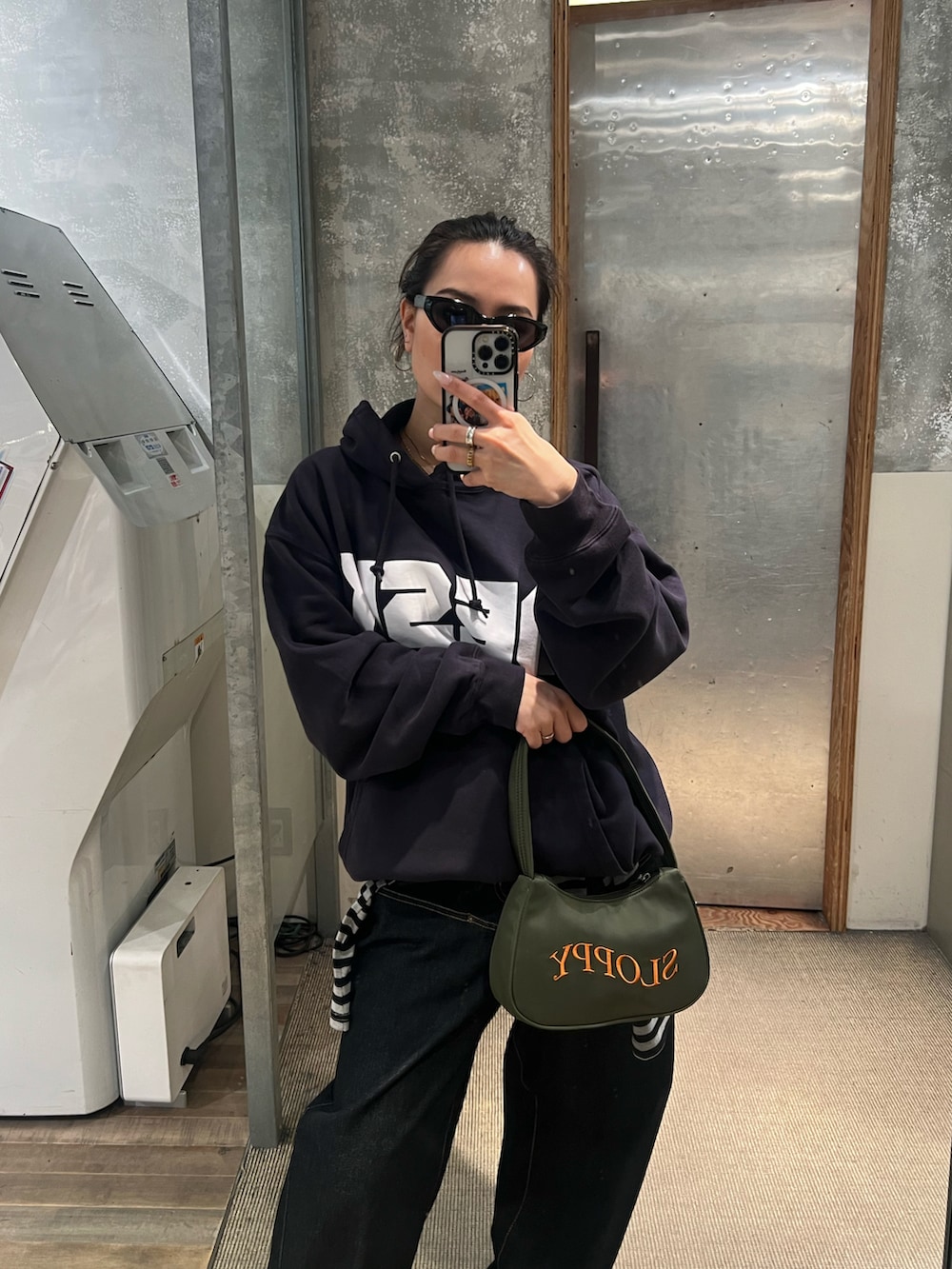 ブルー系のパーカー、ブラック系のショルダーバッグ、ブルー系のデニムパンツを着用したレディースの冬コーディネートの3枚目の写真