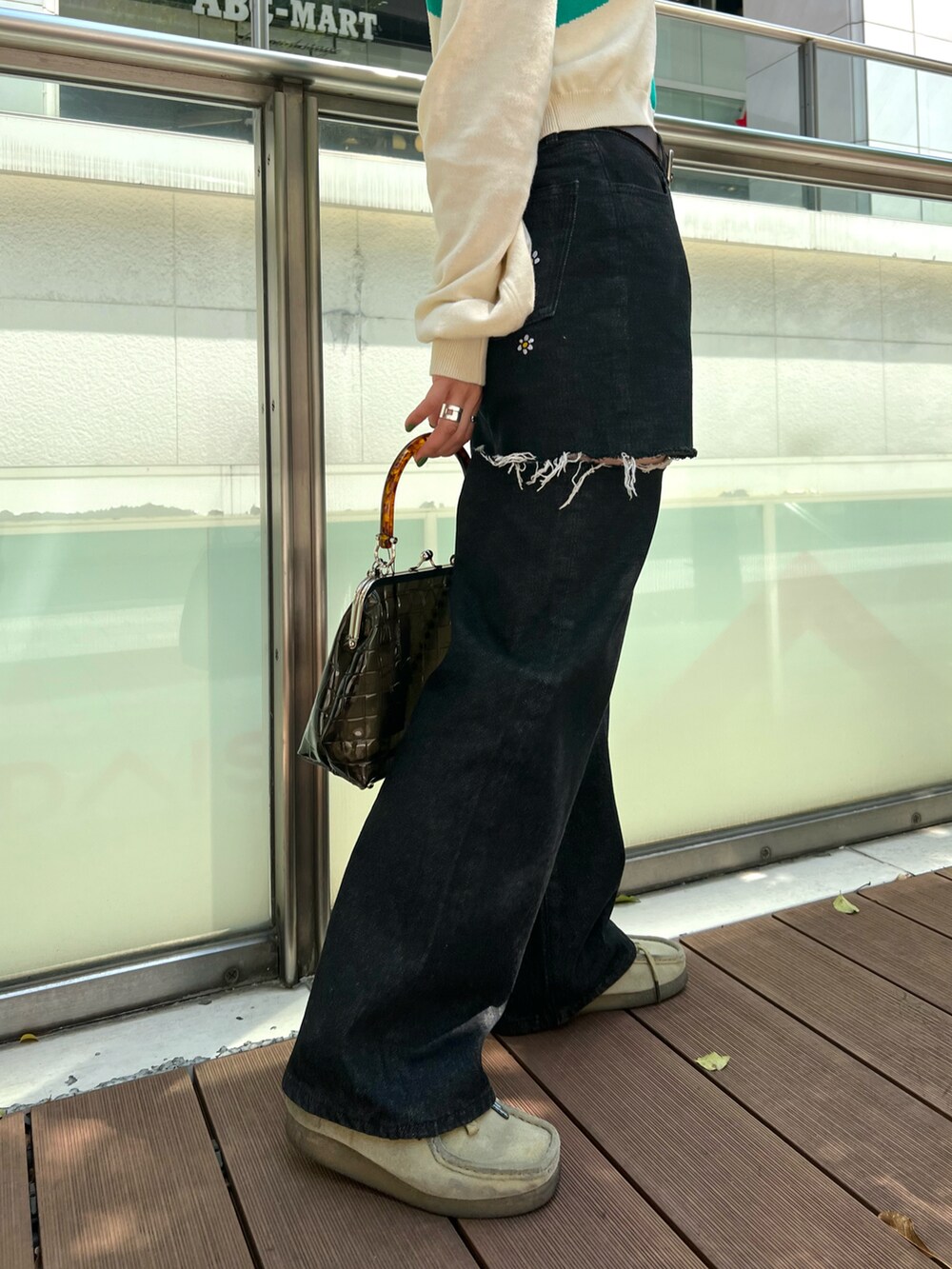 ブラック系のショルダーバッグ、ホワイト系のポロシャツ、ブラック系のデニムパンツを着用したレディースの春コーディネートの2枚目の写真