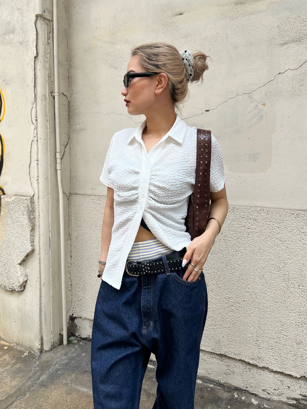 ブルー系のデニムパンツ、ホワイト系のシャツ/ブラウス、ブラック系のショルダーバッグを着用したレディースの夏コーディネートの2枚目の写真