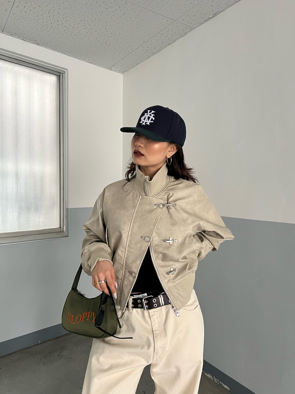 ホワイト系のブルゾン、ブラック系のショルダーバッグ、ホワイト系のデニムパンツを着用したレディースの春コーディネートの2枚目の写真