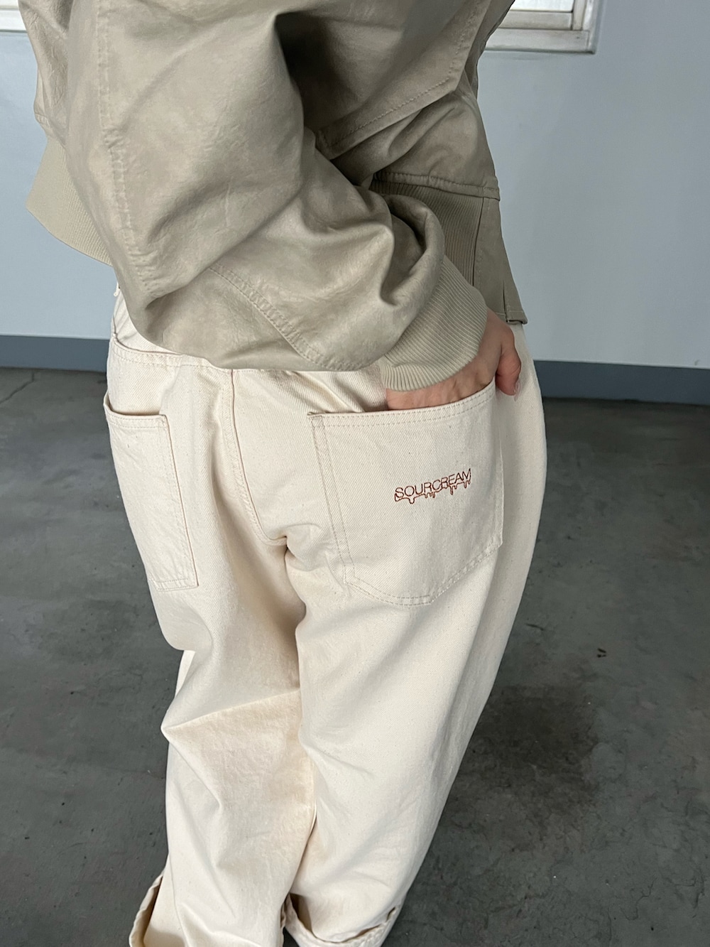 ホワイト系のブルゾン、ブラック系のショルダーバッグ、ホワイト系のデニムパンツを着用したレディースの春コーディネートの3枚目の写真