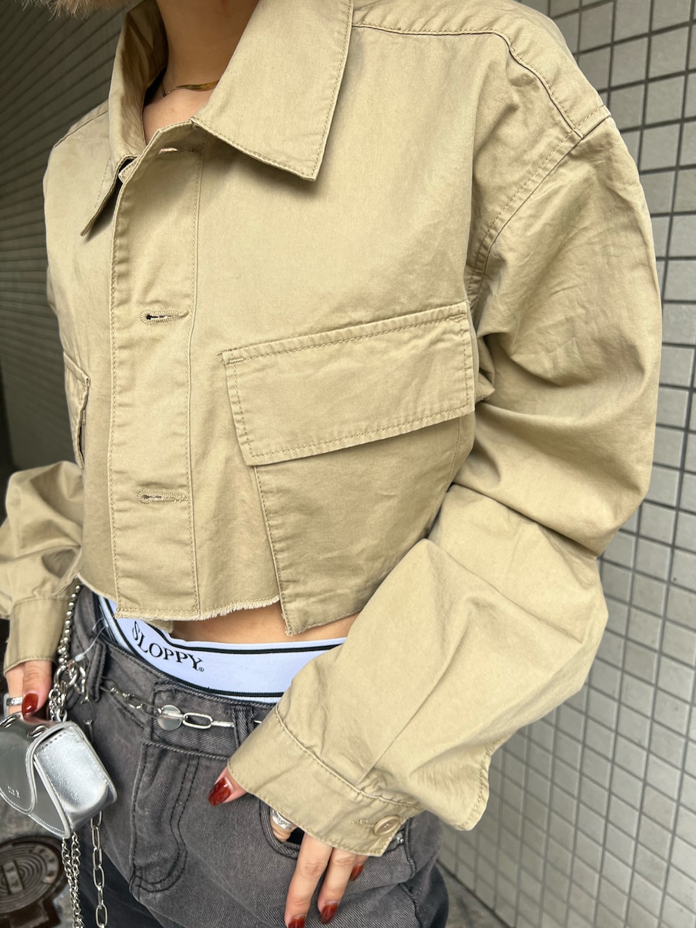 ブラック系のデニムパンツ、ベージュ系のミリタリージャケット、シルバー系のショルダーバッグを着用したレディースの春コーディネートの3枚目の写真