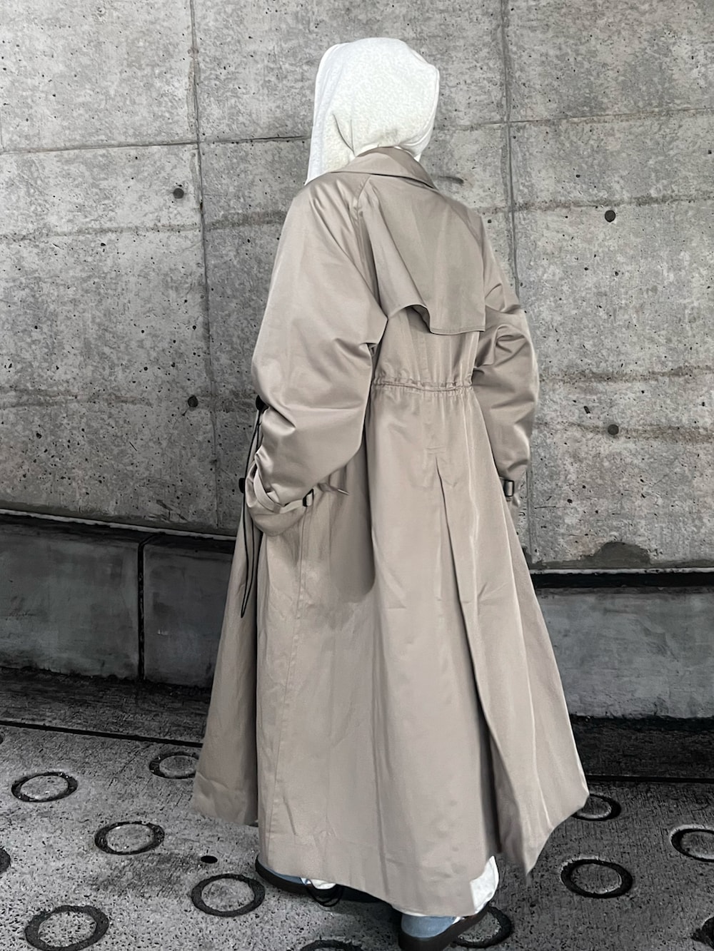 ブルー系のスニーカー、ベージュ系のトレンチコート、グレー系のスウェットパンツを着用したレディースの秋コーディネートの2枚目の写真