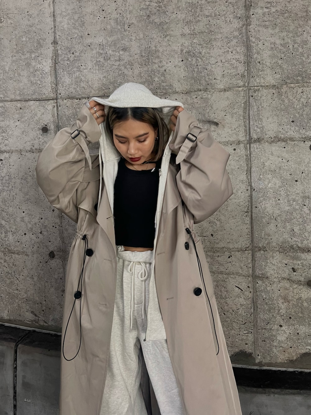 ブルー系のスニーカー、ベージュ系のトレンチコート、グレー系のスウェットパンツを着用したレディースの秋コーディネートの3枚目の写真