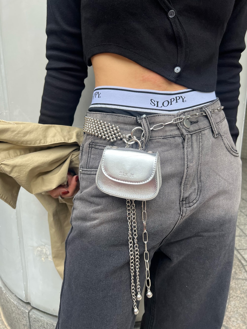 ブラック系のデニムパンツ、ベージュ系のミリタリージャケット、シルバー系のショルダーバッグを着用したレディースの春コーディネートの4枚目の写真