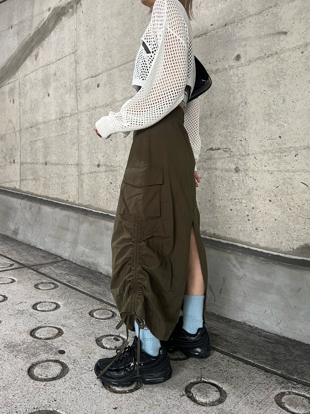 グリーン系のスカート、ホワイト系のニット/セーター、グレー系のキャミソールを着用したレディースの夏コーディネートの3枚目の写真