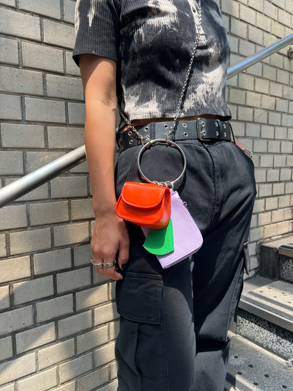 ブラック系のカーゴパンツ、ブラック系のスニーカー、イエロー系のショルダーバッグを着用したレディースの夏コーディネートの4枚目の写真