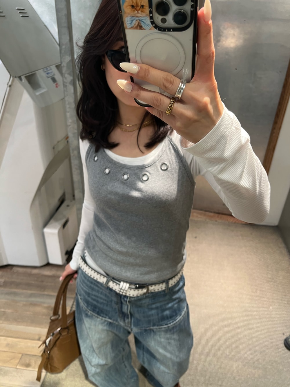 ブルー系のデニムパンツ、グレー系のTシャツ/カットソー、ブラウン系のボストンバッグを着用したレディースの冬コーディネートの3枚目の写真