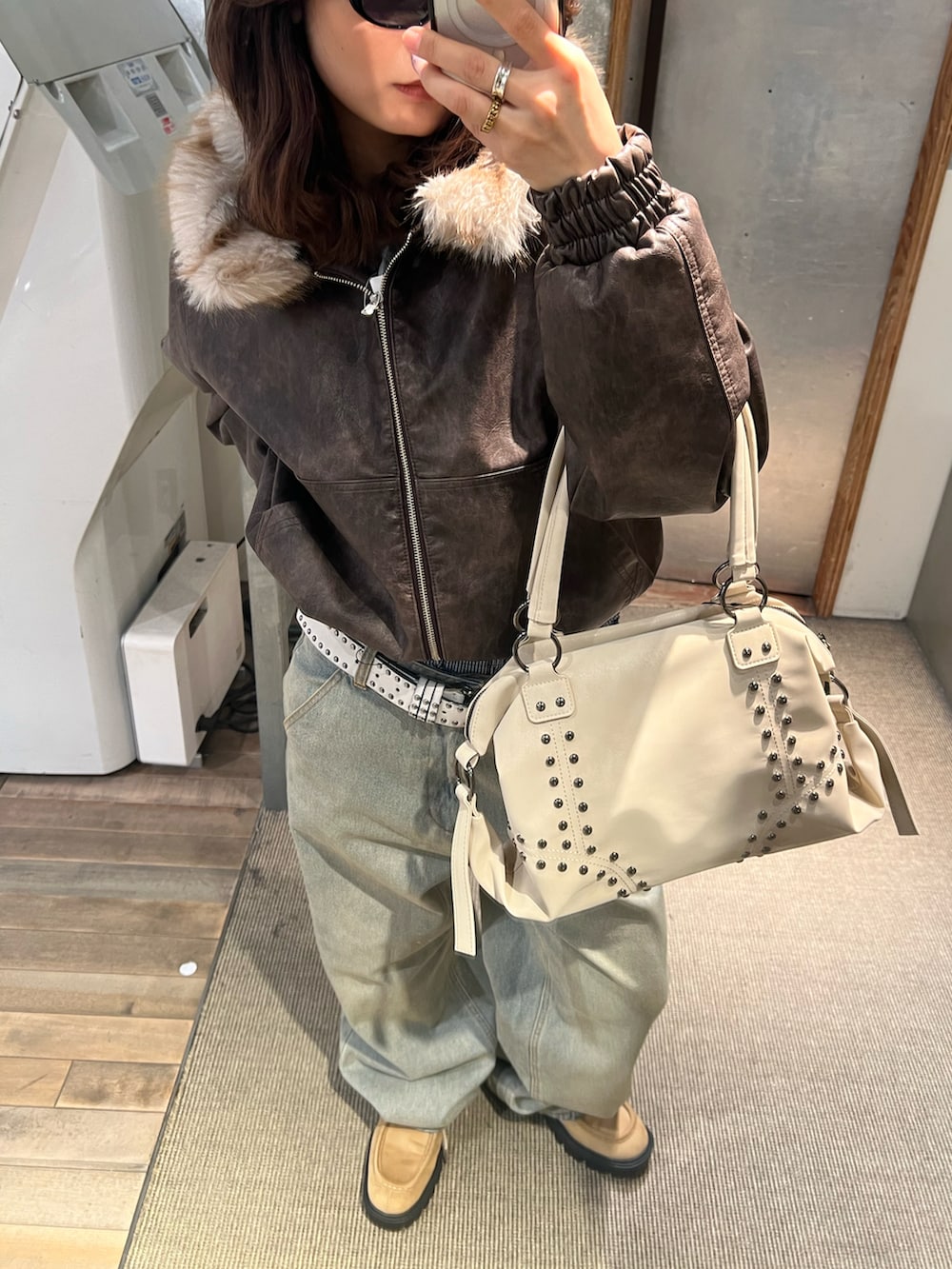 ピンク系のショルダーバッグ、ベージュ系のローファー、ブルー系のデニムパンツを着用したレディースの冬コーディネートの2枚目の写真