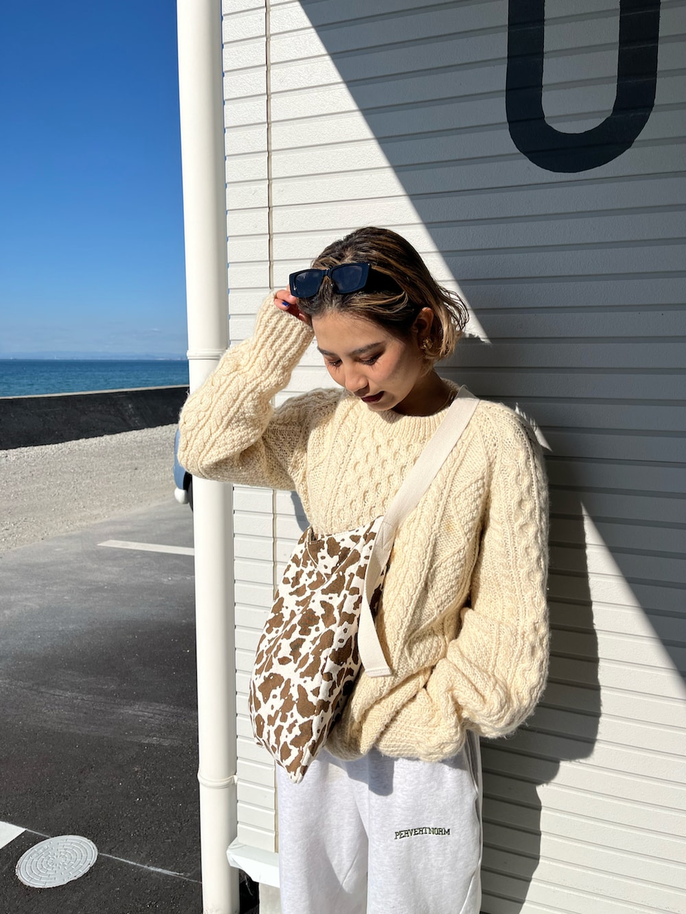 ブラウン系のブーツ、グレー系のスウェットパンツ、ベージュ系のニット/セーターを着用したレディースの秋コーディネートの2枚目の写真