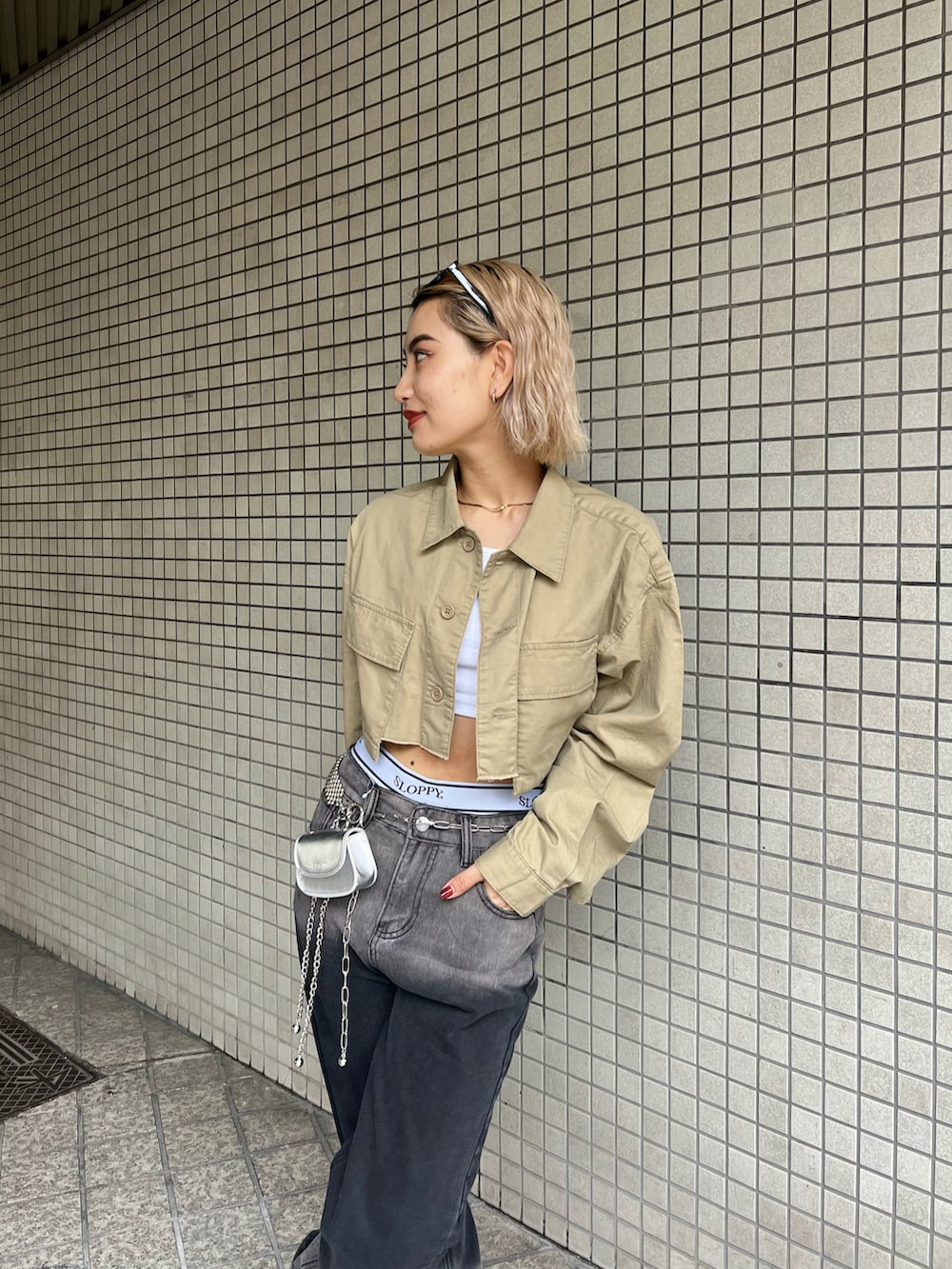 ブラック系のデニムパンツ、ベージュ系のミリタリージャケット、シルバー系のショルダーバッグを着用したレディースの春コーディネートの2枚目の写真