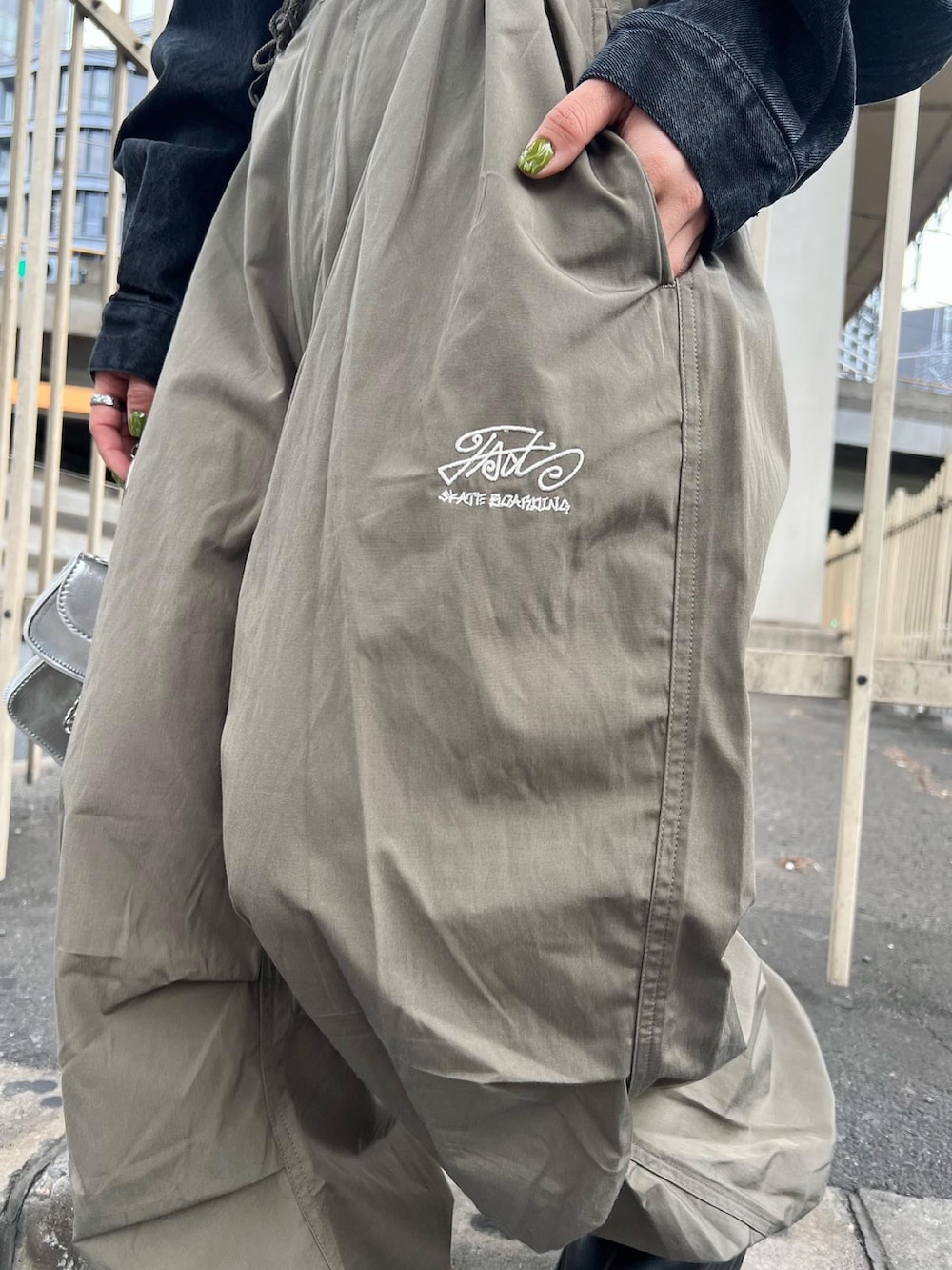 ホワイト系のカーゴパンツ、ブラック系のデニムジャケット、シルバー系のショルダーバッグを着用したレディースの春コーディネートの2枚目の写真