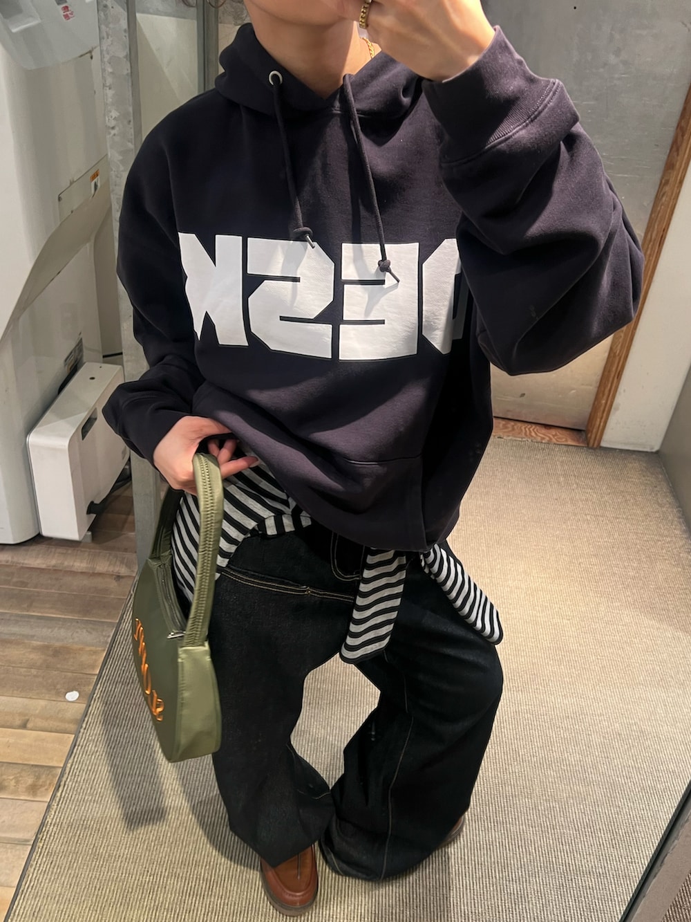 ブルー系のパーカー、ブラック系のショルダーバッグ、ブルー系のデニムパンツを着用したレディースの冬コーディネートの2枚目の写真