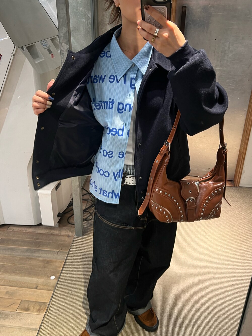 ブルー系のスタジャン、ブルー系のシャツ/ブラウス、ブラウン系のショルダーバッグを着用したレディースの秋コーディネートの3枚目の写真