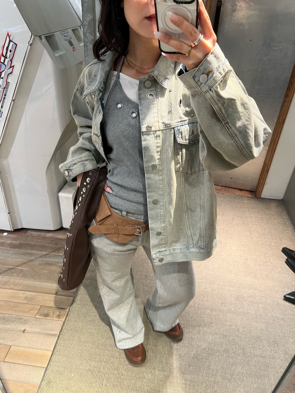 ブルー系のデニムジャケット、グレー系のスウェットパンツ、ブラウン系のショルダーバッグを着用したレディースの冬コーディネートの2枚目の写真