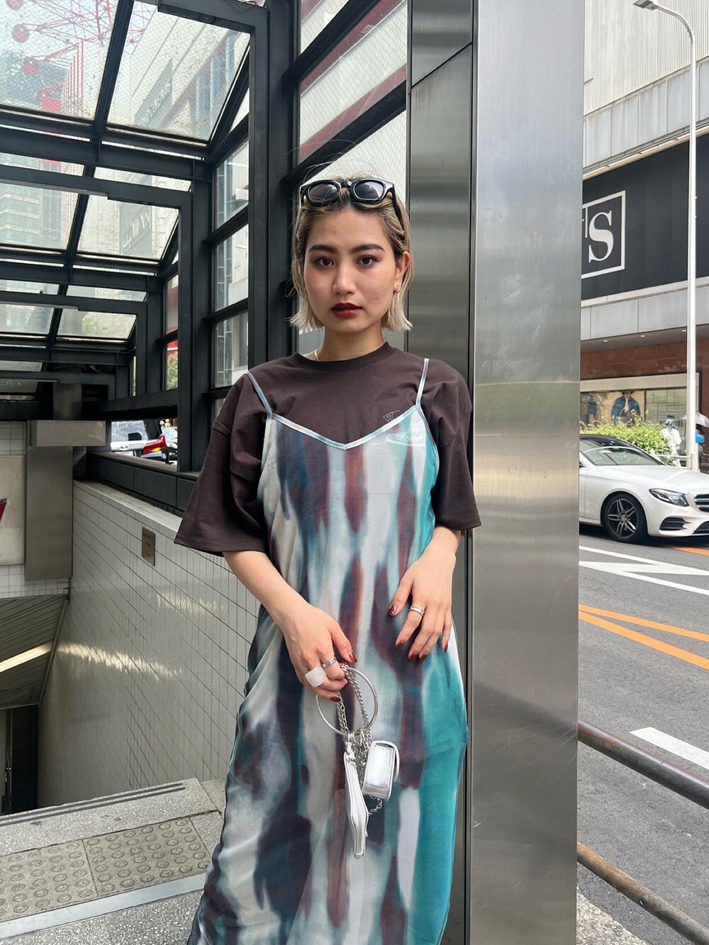 ブラック系のデニムパンツ、ブラウン系のTシャツ/カットソー、パープル系のワンピースを着用したレディースの春コーディネートの4枚目の写真