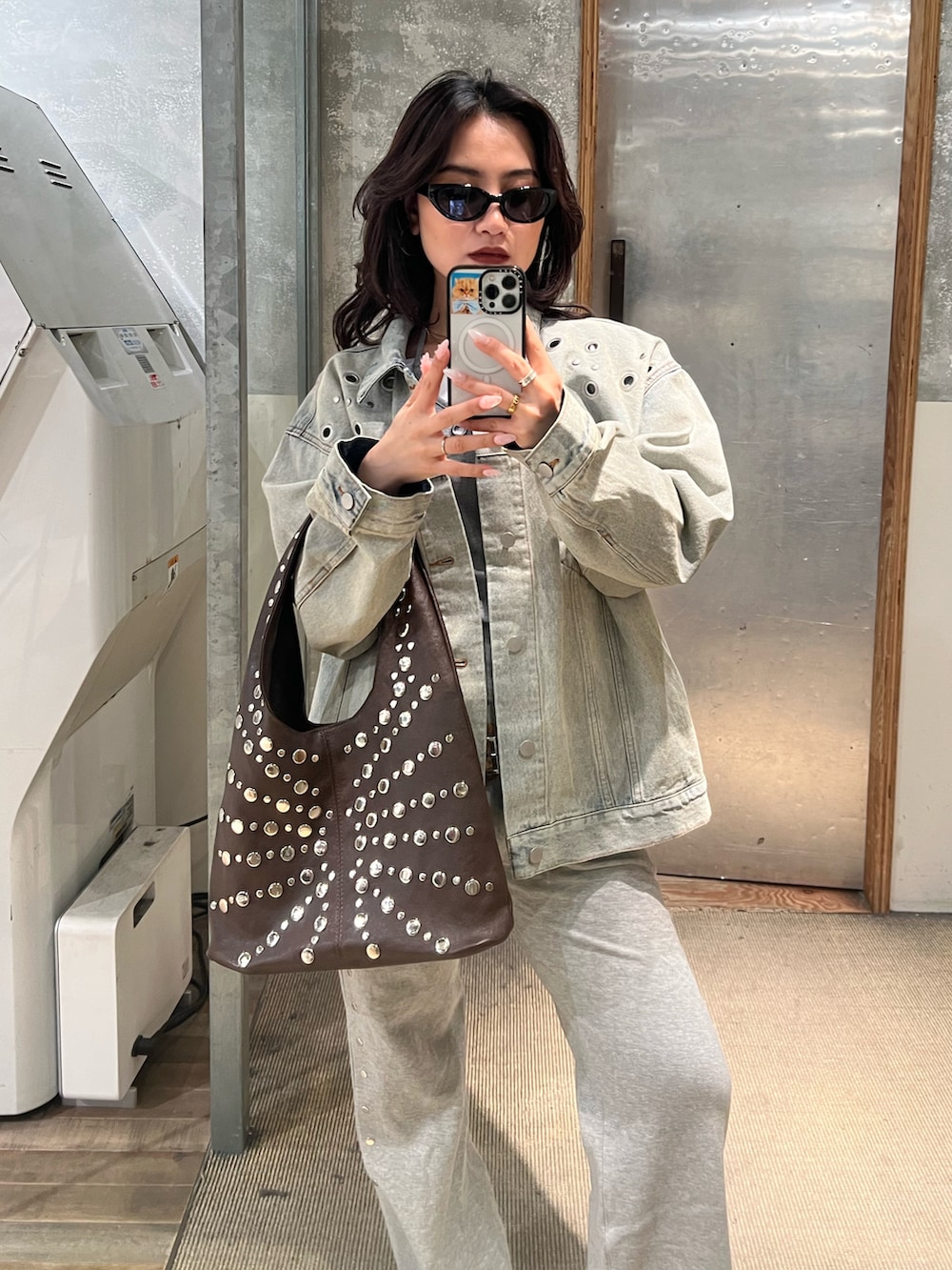 ブルー系のデニムジャケット、グレー系のスウェットパンツ、ブラウン系のショルダーバッグを着用したレディースの冬コーディネートの3枚目の写真