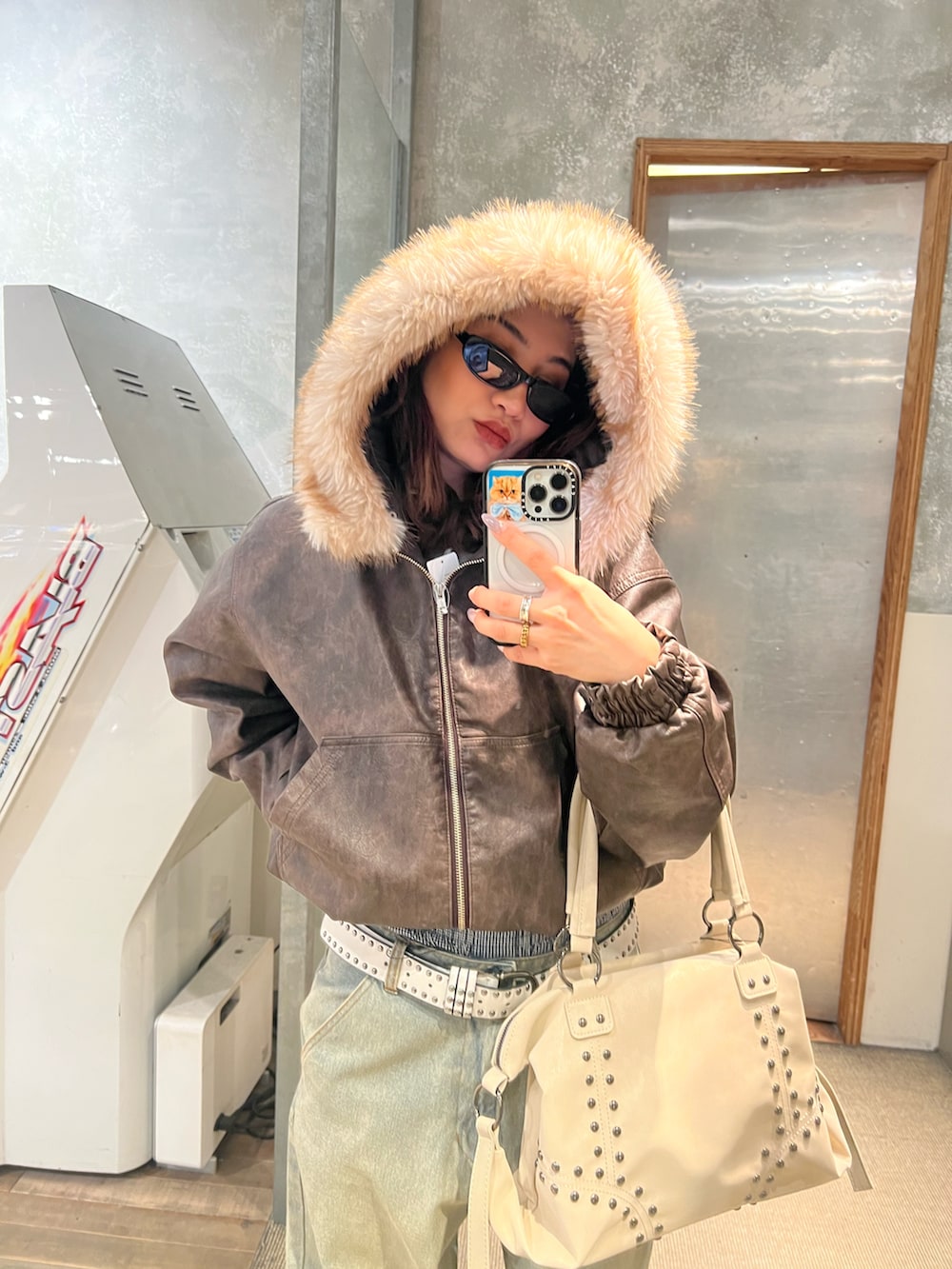 ピンク系のショルダーバッグ、ベージュ系のローファー、ブルー系のデニムパンツを着用したレディースの冬コーディネートの3枚目の写真