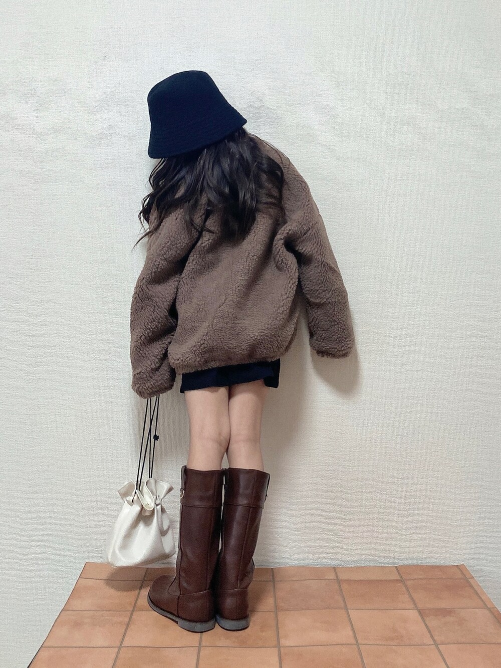 ブラウン系のブルゾン、ブラウン系のブーツ、ホワイト系のハンドバッグを着用したキッズの冬コーディネートの3枚目の写真