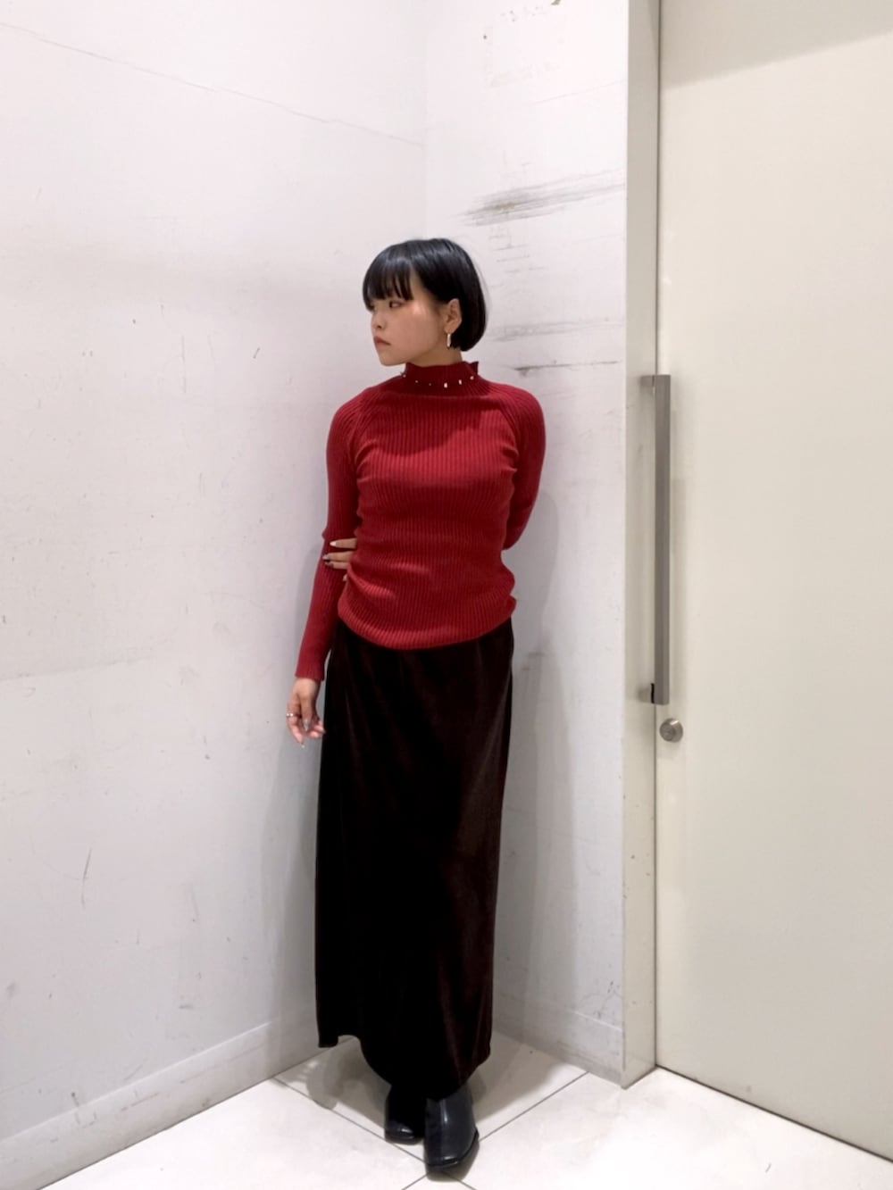 レッド系のニット/セーター、ブラウン系のスカートを着用したレディースの冬コーディネートの2枚目の写真