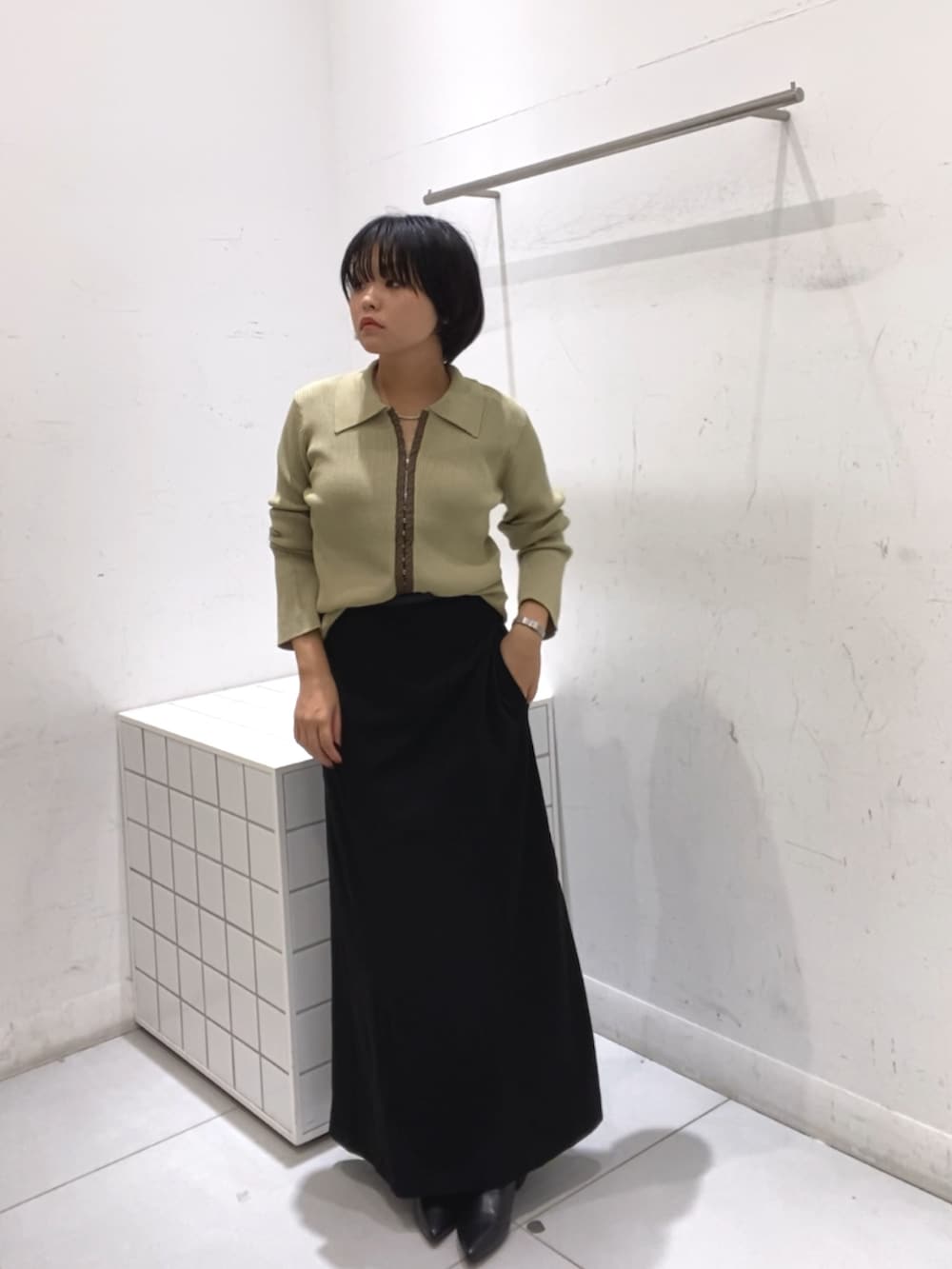 ブラック系のスカート、イエロー系のカーディガン/ボレロ、ブラック系のブーツを着用したレディースの秋コーディネートの2枚目の写真